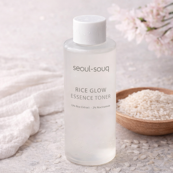 Bottle of Seoul-souq Rice Glow Essence Toner on a light background with rice and flowers.
